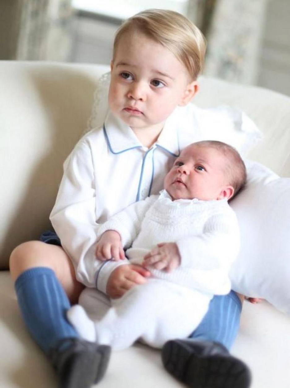 Na fotografijah princ George drži v rokah komaj nekaj tednov staro sestrico princeso Charlotte.