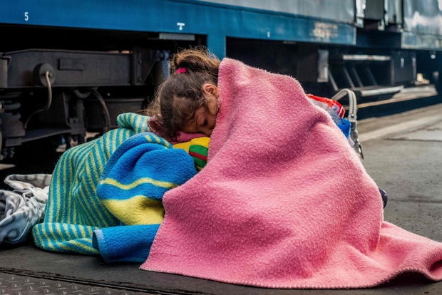 Begunska deklica spi na železniški postaji Keleti v Budimpešti, čakajoč, da jih spustijo naprej.