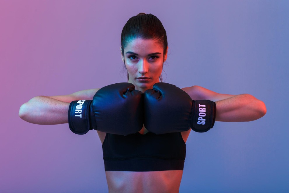 Photo of beautiful strong young sports woman make exercises with gym barbell disk isolated over purple wall background. Looking aside.