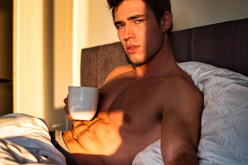 Young man shirtless on his bed with a coffee or tea cup (foto: Shutterstock)